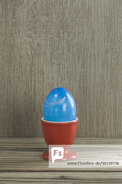 Roter Eierbecher mit blauem Osterei