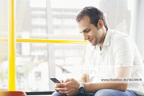 Man sitting in public transport looking at his smartphone