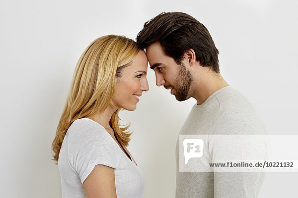 Ein glückliches verliebtes Paar  das sich von Kopf zu Kopf vor weißem Hintergrund ansieht.