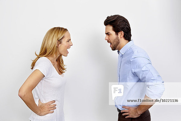 Angry couple shouting at each other in front of white background