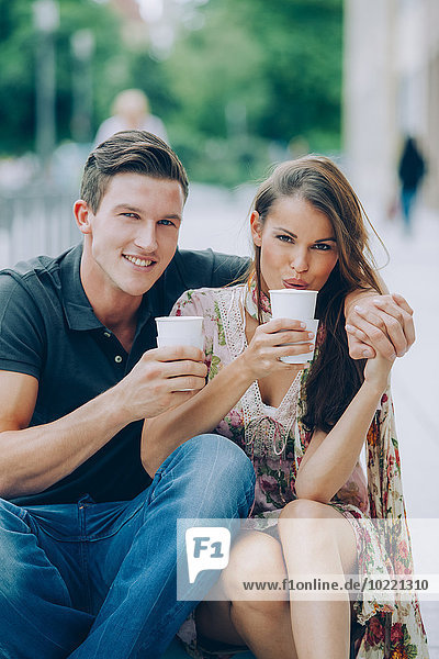 Smiling young couple drinking coffee outdoors