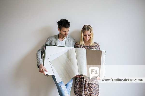 Young couple holding a catalogue selecting wallpaper for their new home