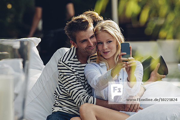 Young woman taking a selfie of herself and her boyfriend in an outdoor cafe