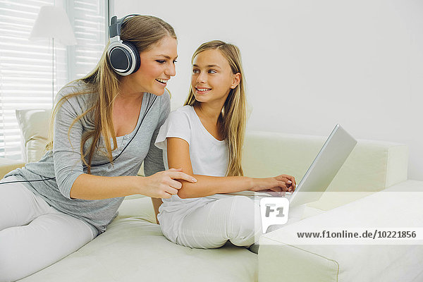 Mother and daughter on couch with laptop and headphones