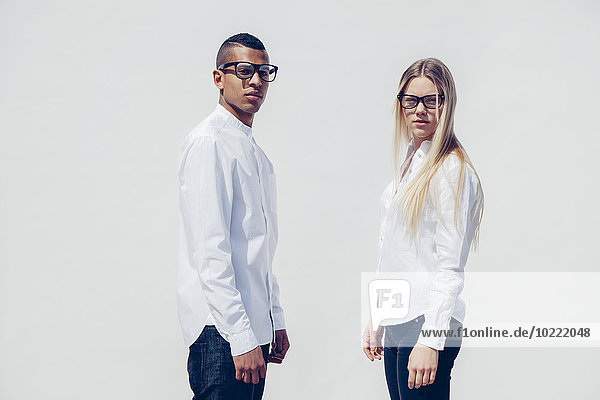 Portrait of stylish young couple wearing matching clothes in front of white background