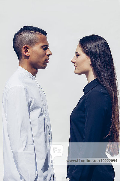 Stilvolles junges Paar von Angesicht zu Angesicht vor weißem Hintergrund