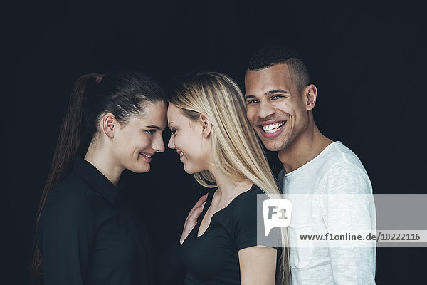Gruppenbild von zwei jungen Frauen und einem jungen Mann vor schwarzem Hintergrund