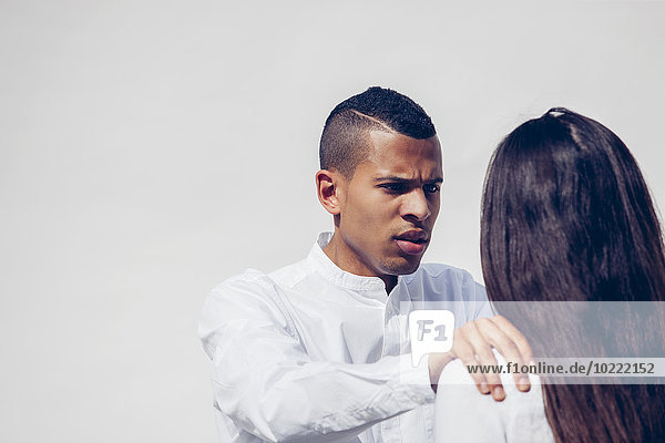 Porträt eines wütenden jungen Mannes von Angesicht zu Angesicht mit seiner Freundin vor weißem Hintergrund.