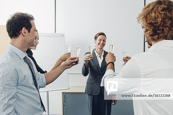 Group of business people raising a toast with champagne at office