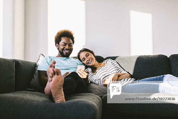 Young couple lying on couch looking at smart phone