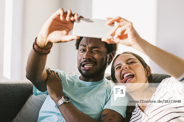 Glückliches junges Paar fotografiert sich selbst mit dem Smartphone