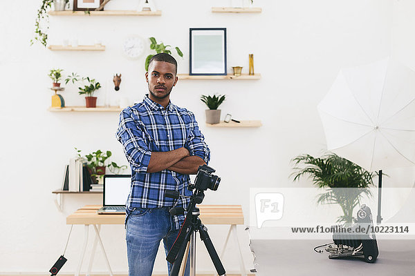 Portrait of young man standing in his photographic studio