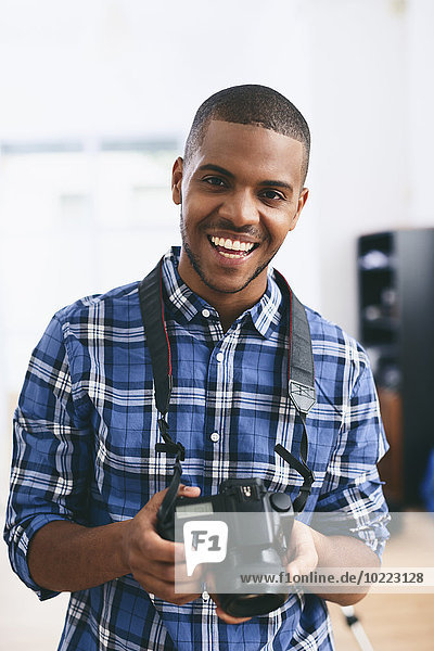 Portrait of smiling young man in his photographic studio