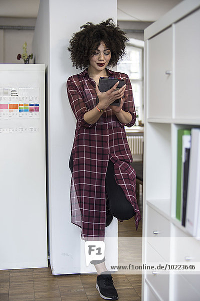 Young woman in office using digital tablet