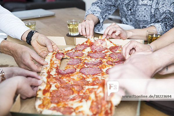 Kollegen im Büro teilen sich Pizza