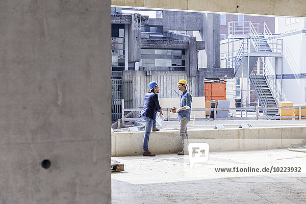Zwei Männer mit Schutzhelmen im Gespräch auf der Baustelle