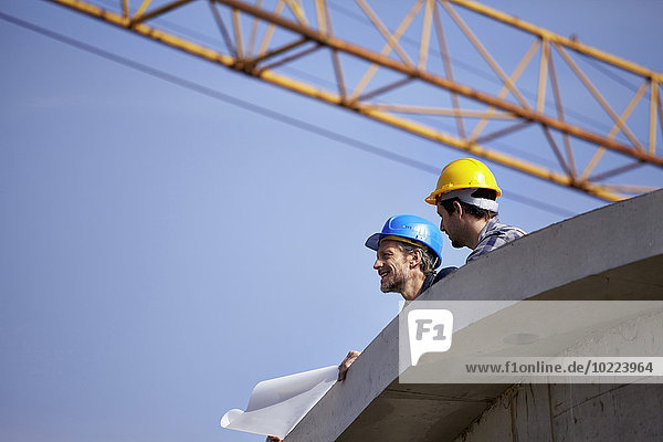 Two men on construction site with construction plan