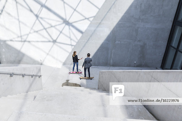 Zwei Geschäftsleute auf Skateboards in moderner Architektur