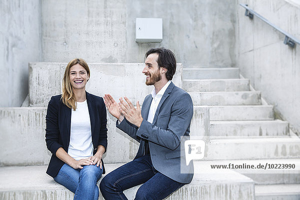 Two business people sitting on concrete steps