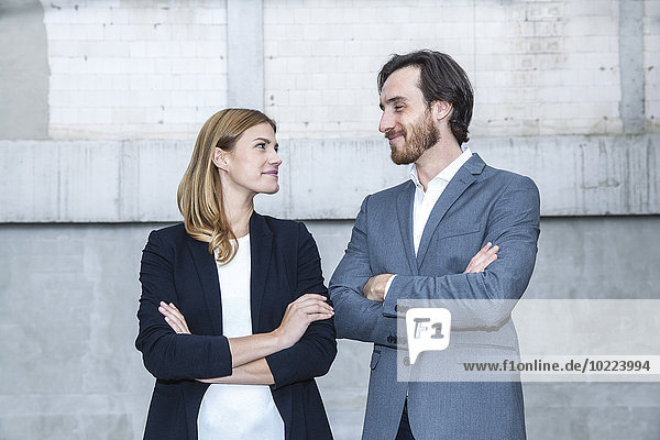 Two business people standing face to face with crossed arms