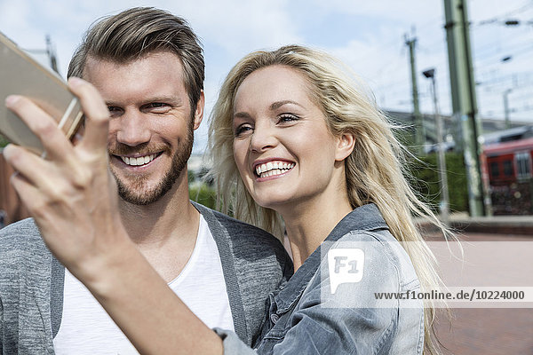 Germany  Cologne  young couple taking a selfie with smartphone