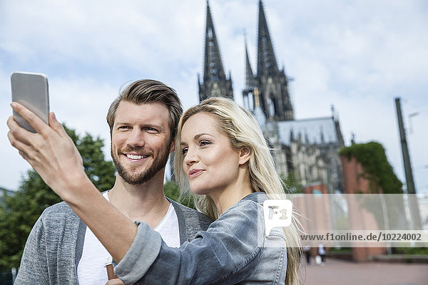 Germany  Cologne  young couple taking a selfie with smartphone