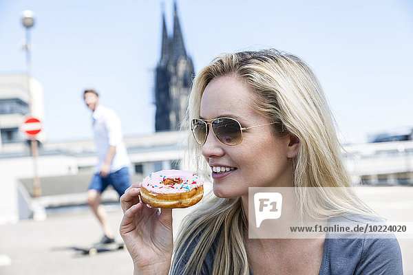 Germany  Cologne  portrait of young woman eating bagel