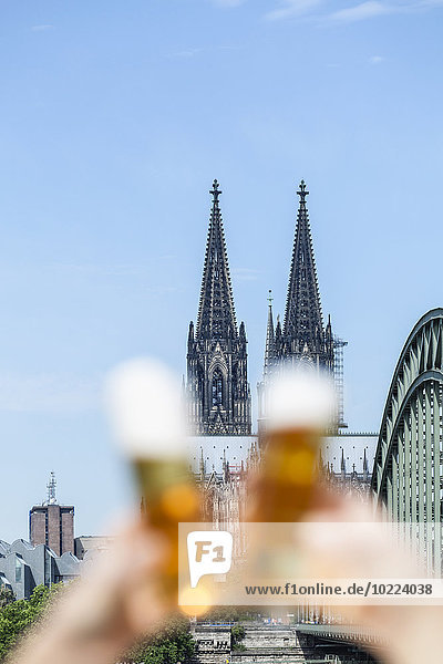 Germany  Cologne  couple toasting with Koelsch glasses in front of Cologne Cathedral