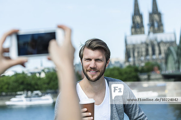 Germany  Cologne  young woman taking a picture of her boyfriend with smartphone