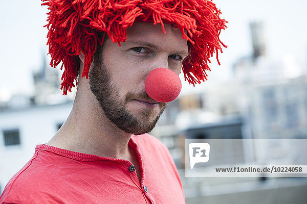 Germany  Cologne  portrait of bearded young man wearing clown's nose and red wig