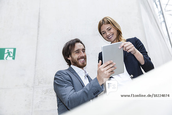 Zwei lächelnde Geschäftsleute beim Betrachten des digitalen Tabletts