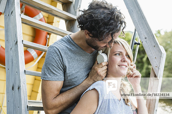Couple having a trip on a house boat sharing headphones