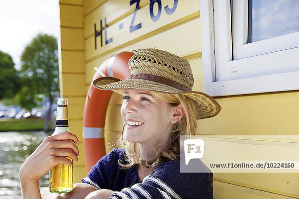 Lächelnde Frau auf einem Hausboot mit Bierflasche