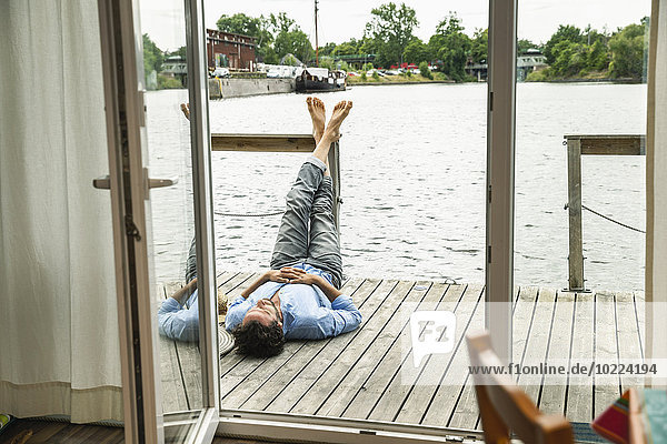 Mann auf Holzdeck eines Hausbootes liegend