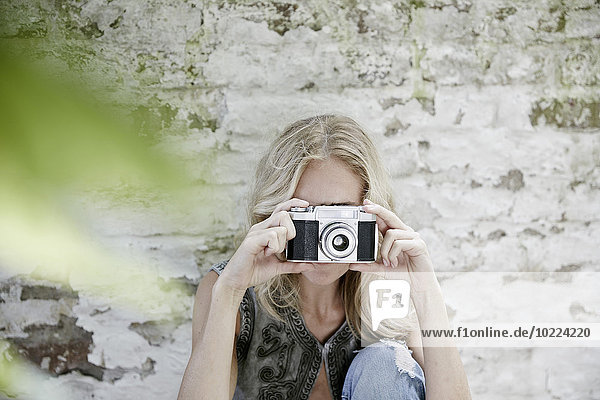 Blonde Frau beim Fotografieren mit einer alten Kamera