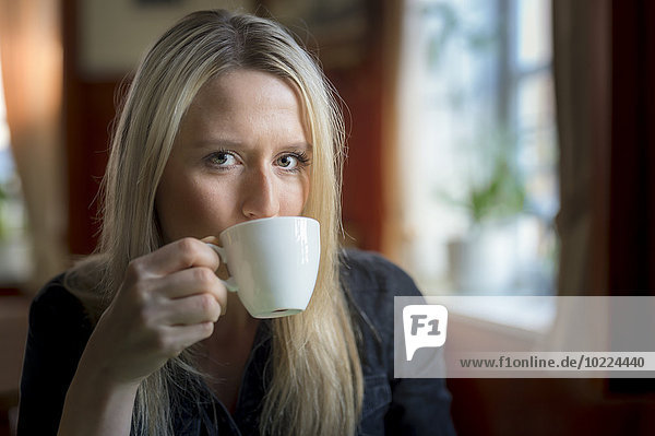 Porträt einer blonden Frau beim Kaffeetrinken