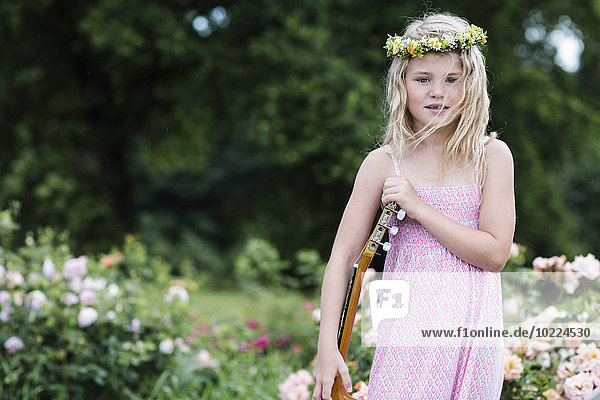 Porträt eines kleinen Mädchens mit Gitarre in Blumenkranz
