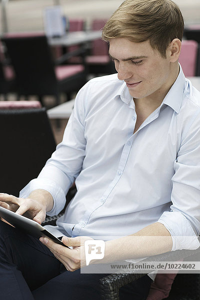 Junger Mann sitzt im Coffee-Shop mit digitalem Laptop