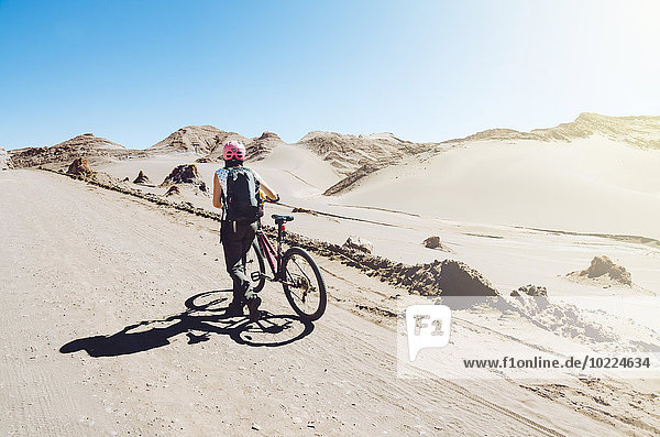 Chile  woman pushing a mountain bike through the Moon Valley  Atacama Desert