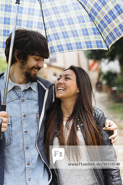 Glückliches junges Paar mit Regenschirm