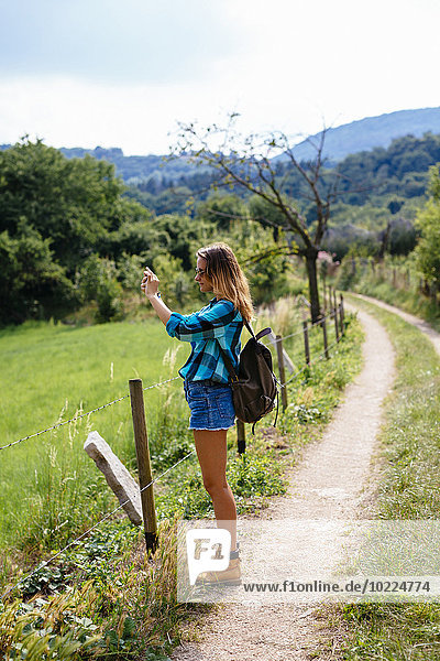 Südtirol  Teenagermädchen mit Rucksack auf einem Weg stehend und fotografierend