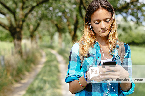 Teenagerin mit Smartphone und Kopfhörer