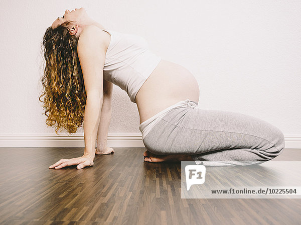 Schwangere Frau auf Holzboden  die sich zurücklehnt