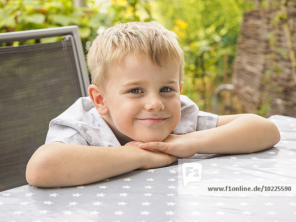 Porträt eines lächelnden blonden Jungen auf der Terrasse