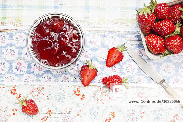 Glas Erdbeermarmelade und Schachtel Erdbeeren
