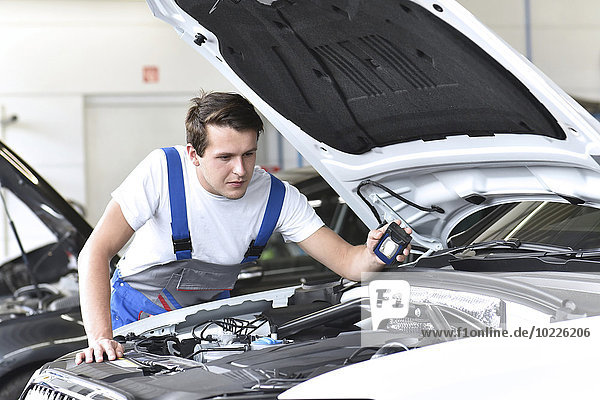 Mechanic examining engine of a car in a garage