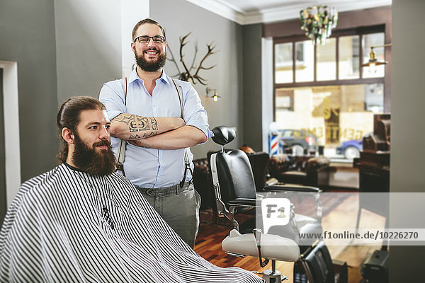 Portrait of smiling barber with customer in barber shop
