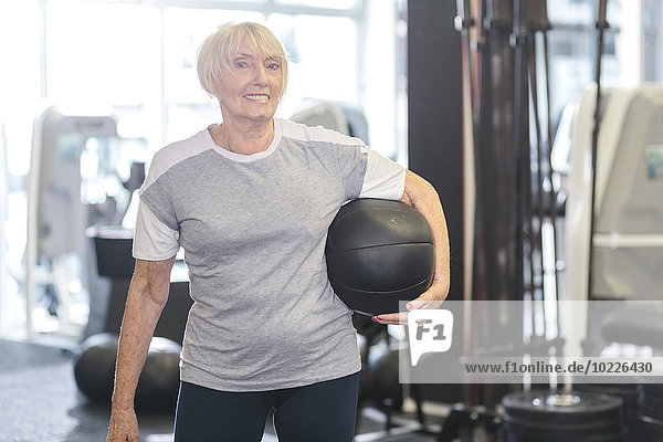 Senior woman in gym holding medicine ball