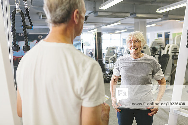 Senior woman smiling at man in gym