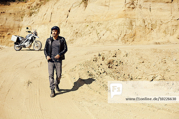 Erwachsener Mann mit Motorrad im Sandkasten